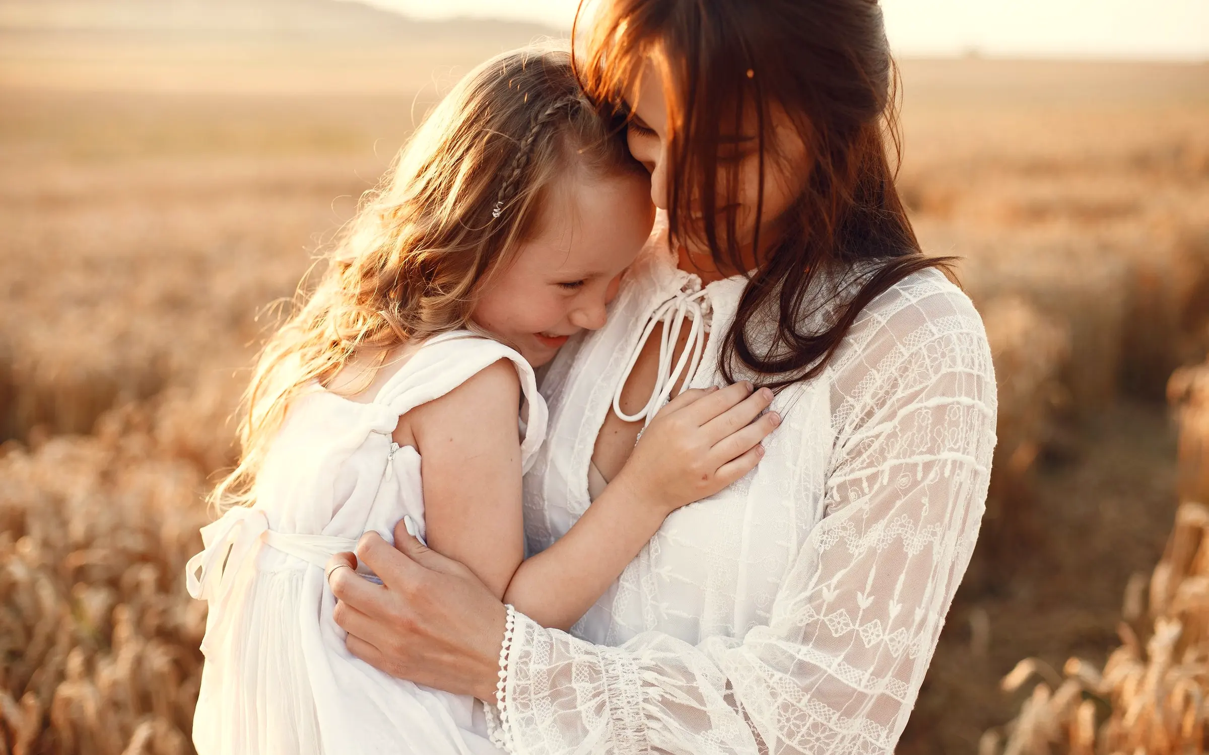 Mãe e filha abraçadas num campo ao entardecer